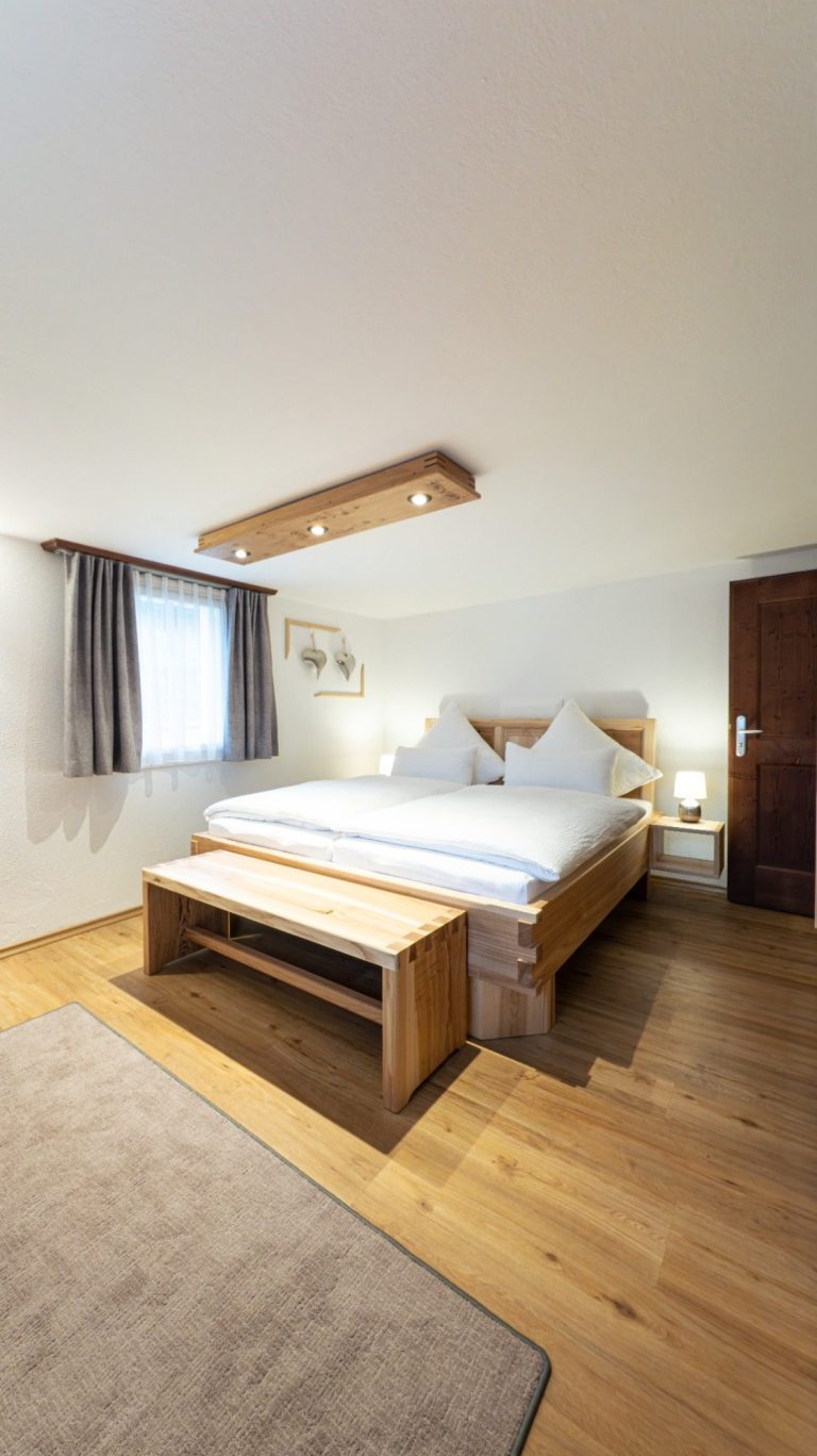 Helles Schlafzimmer mit einem großen Bett, Holzfußboden und modernen Lampen.