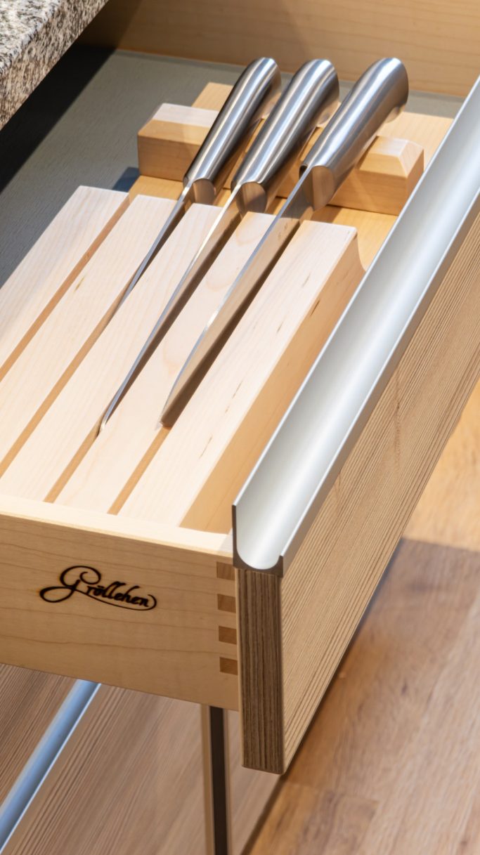Holzschneiderblock mit drei glatten, silbernen Messern.