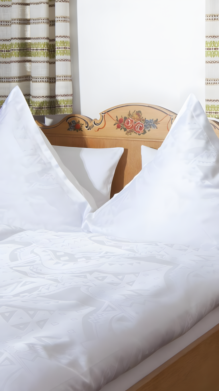 Zwei große, weiße Kissen auf einem Bett mit einem dekorativen Kopfteil.