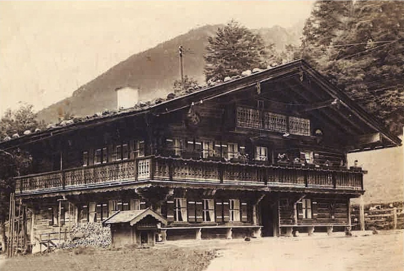 Altes alpenländisches Holzhaus mit Balkon und umgebenden Baum.