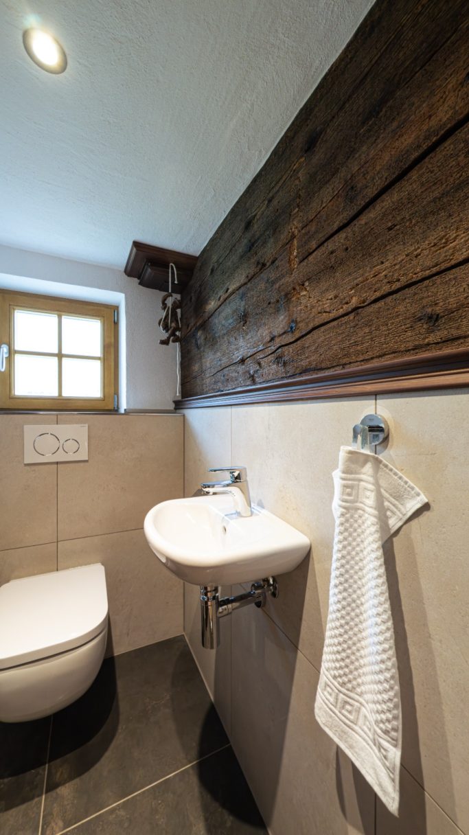 Ein modernes Badezimmer mit Holzverkleidung, Waschbecken und Handtuchhalter.