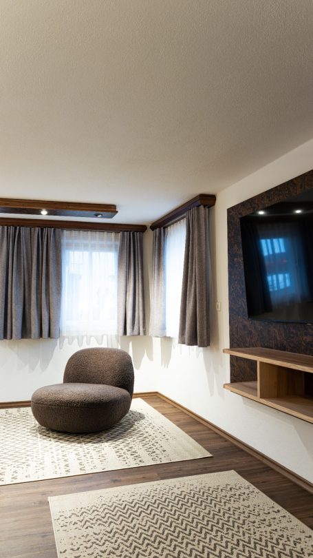 Moderne Wohnzimmereinrichtung mit rundem Sessel und TV-Anlage an der Wand.