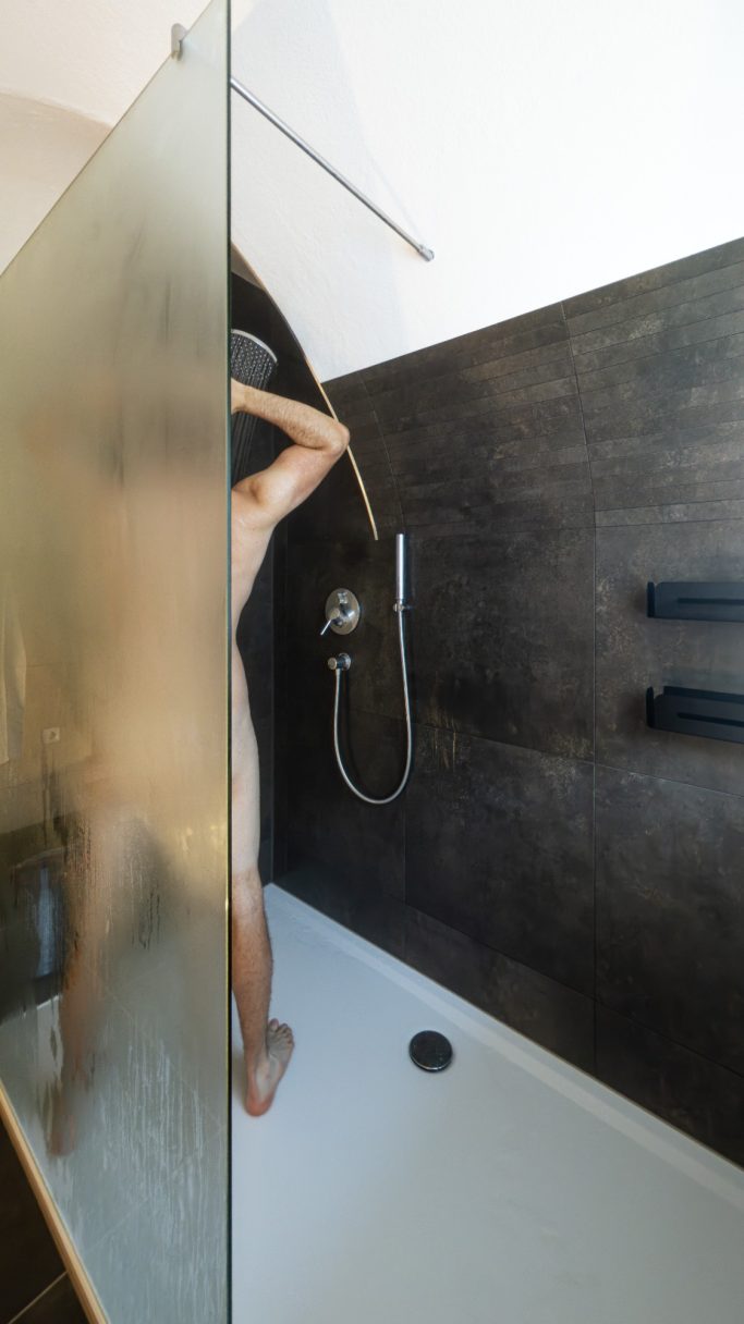 Person steht unter einer Dusche in einem modernen Badezimmer.