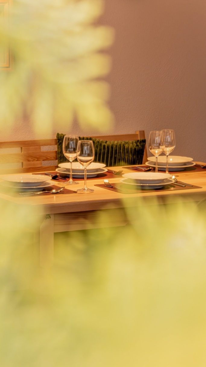 Ein gedeckter Tisch mit Gläsern und Tellern in einem gemütlichen Ambiente.