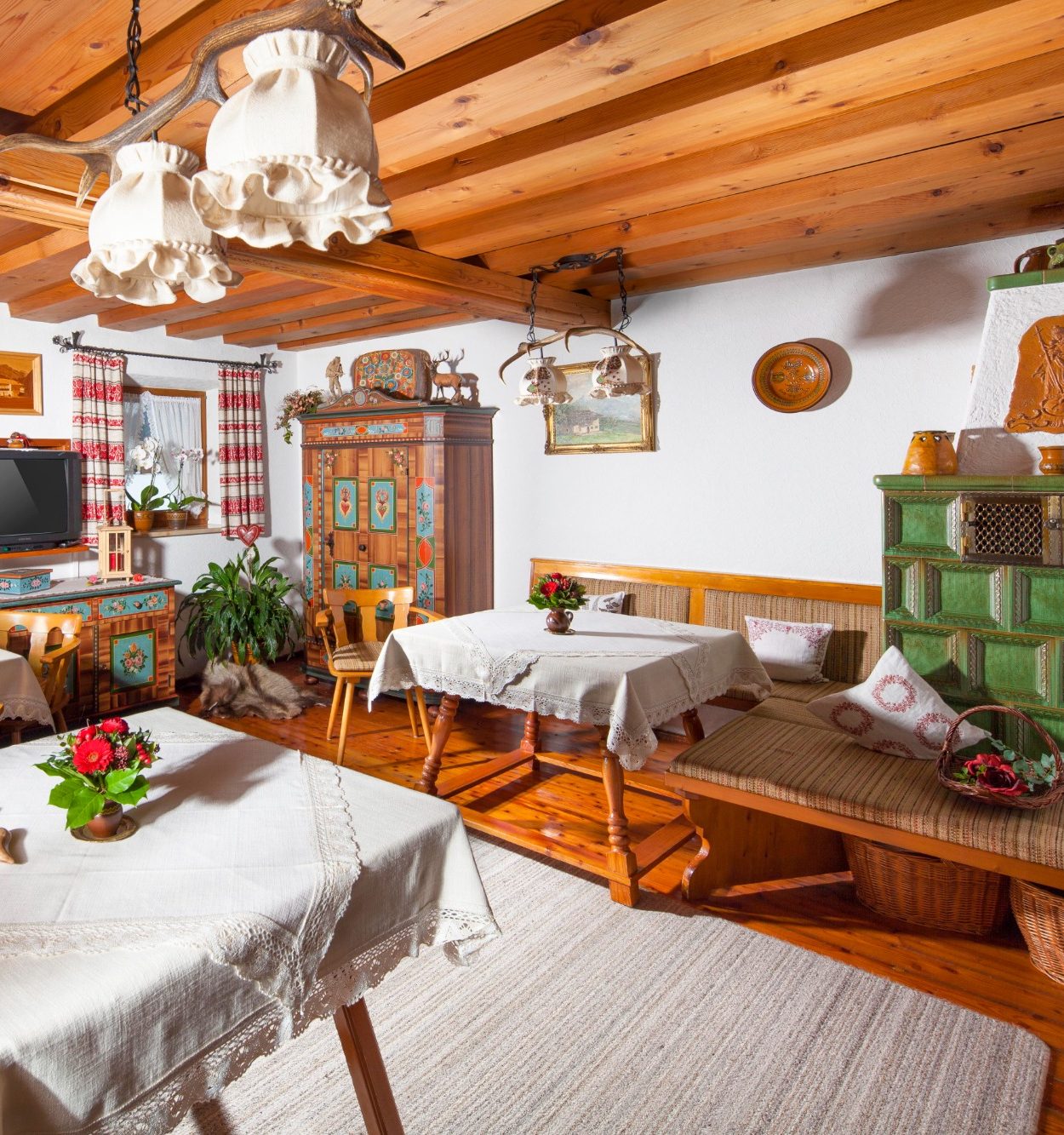 Gemütlicher, traditioneller Raum mit Holzmöbeln, Tischdecken und Pflanzen.