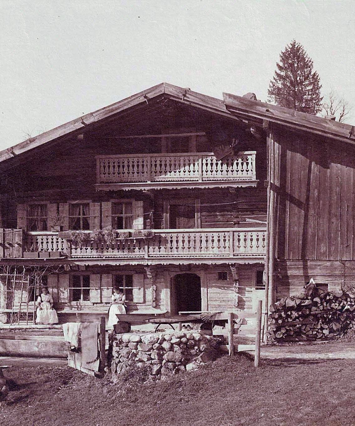 Traditionelles altes Holzhaus in den Alpen, mit Balkonen und gestapeltem Holz.