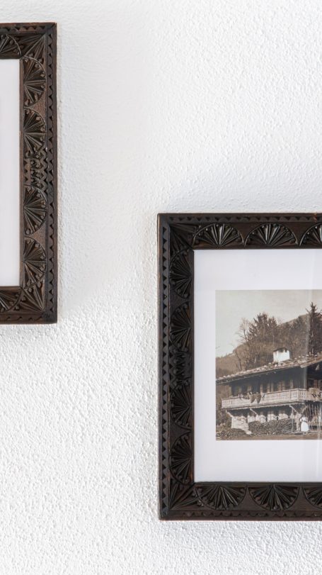 Zwei dekorative Bilderrahmen mit historischen Fotografien, an einer weißen Wand hängend.