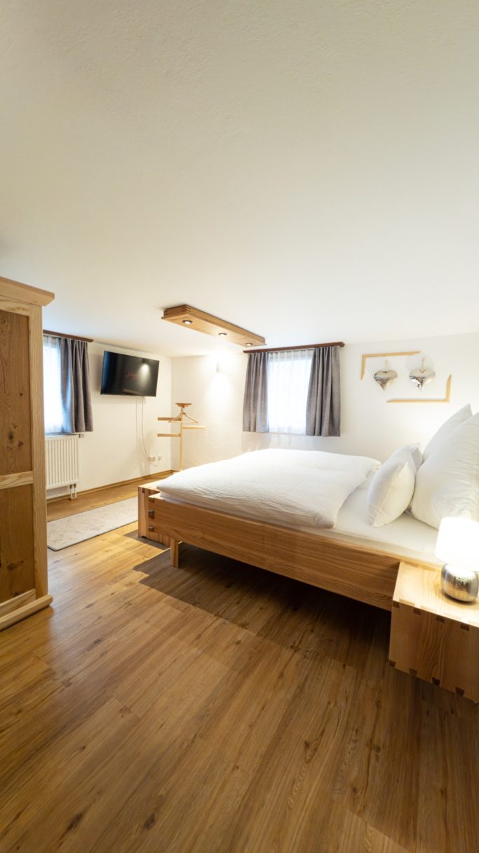 Helles Schlafzimmer mit Holzfußboden, Doppelbett und moderner Ausstattung.