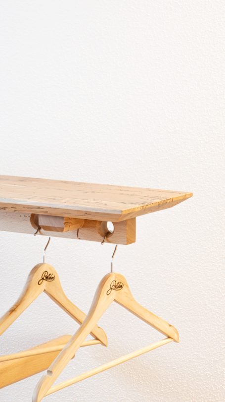 Holztisch mit zwei Holzkleiderbügeln, vor einer weißen Wand.