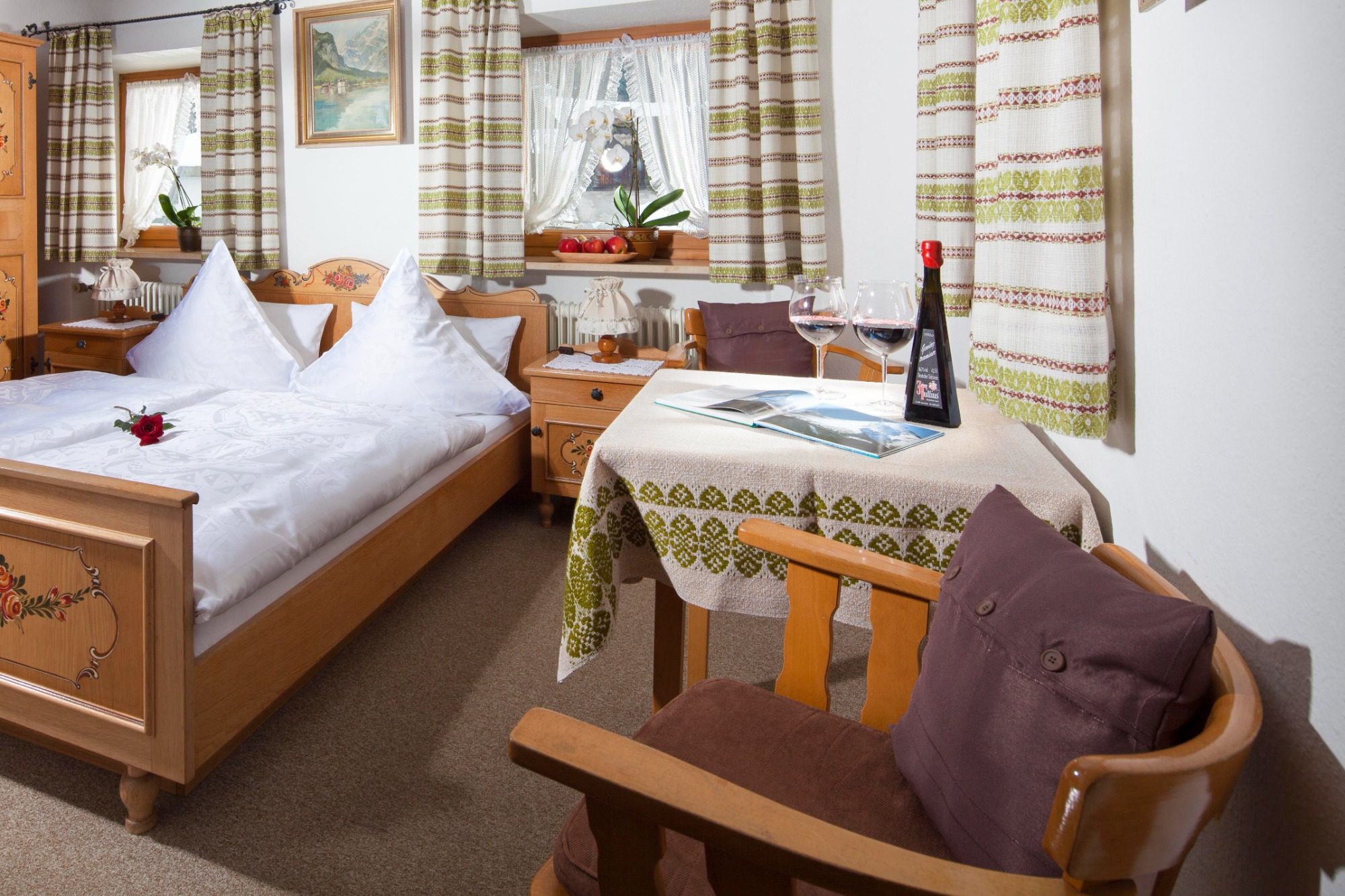 Ein gemütliches Zimmer mit einem Doppelbett, Tisch, Stuhl und Weinflasche.